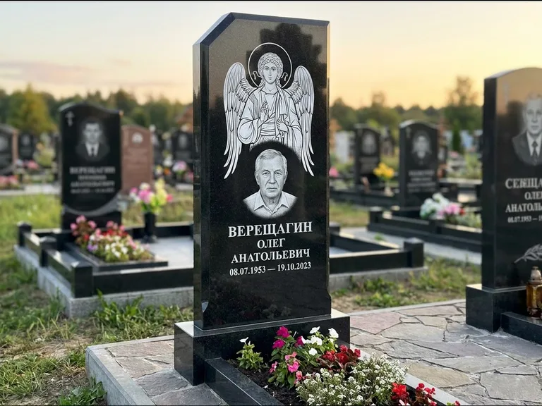 Памятник с гравировкой иконы: стела с резным навершием и нимбом в золоте — гравировка образа Спасителя, высокие разросшиеся туи полукругом, работа «Мельникова» в Нижнем Новгороде