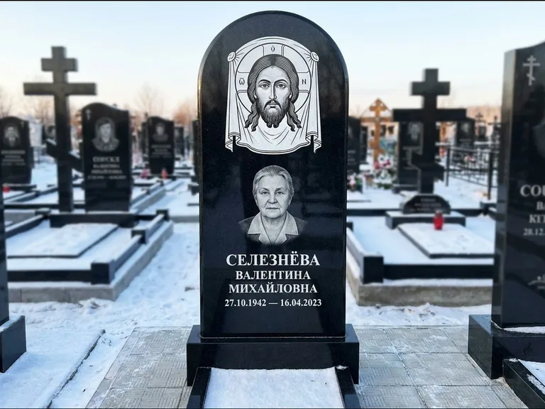 Памятник с гравировкой иконы: небольшая скромная одиночная стела с именной иконой — золочёный нимб на образе, аккуратный участок с газоном, работа «Ковалёв» в Нижнем Новгороде
