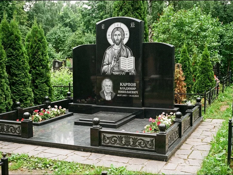 Памятник с гравировкой иконы: широкая панорамная стела с золочёным нимбом — гравировка образа Матроны Московской, цветник с белыми хризантемами, работа «Мельникова» в Нижнем Новгороде