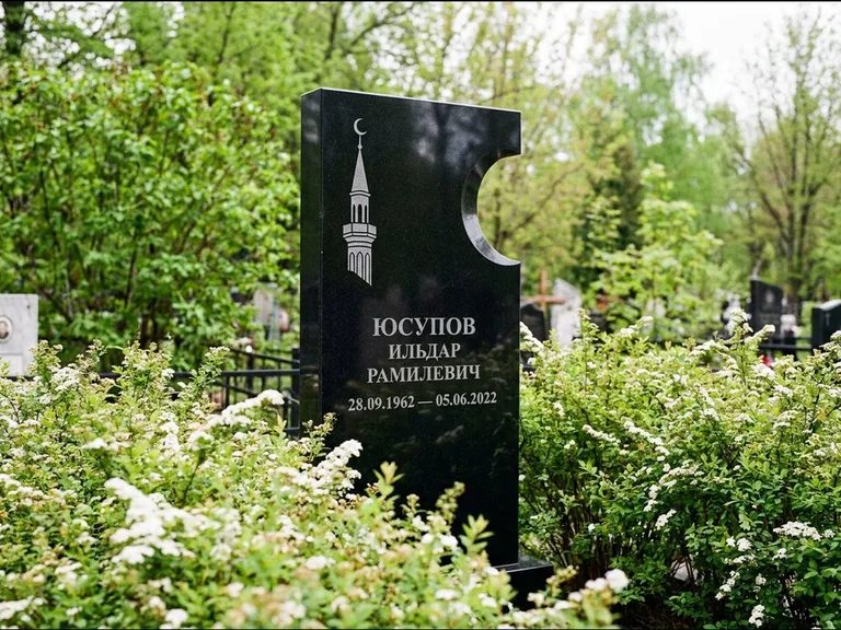 Мусульманский памятник с гравировкой мечети: стела с боковым вырезом в форме полумесяца — гравировка минарета с полумесяцем, низкие кусты спиреи в цвету, работа «Юсупов» в Нижнем Новгороде
